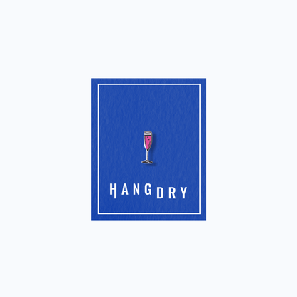 Hang Dry Sunday Dinner enamel pin — champagne flute shape, displayed on Hang Dry blue branded card