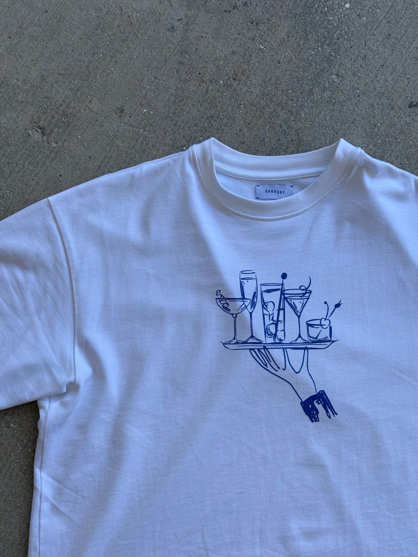 Hang Dry Gallery White Sunday Dinner tee — front view of the hand and cocktail tray graphic on a premium cotton tee