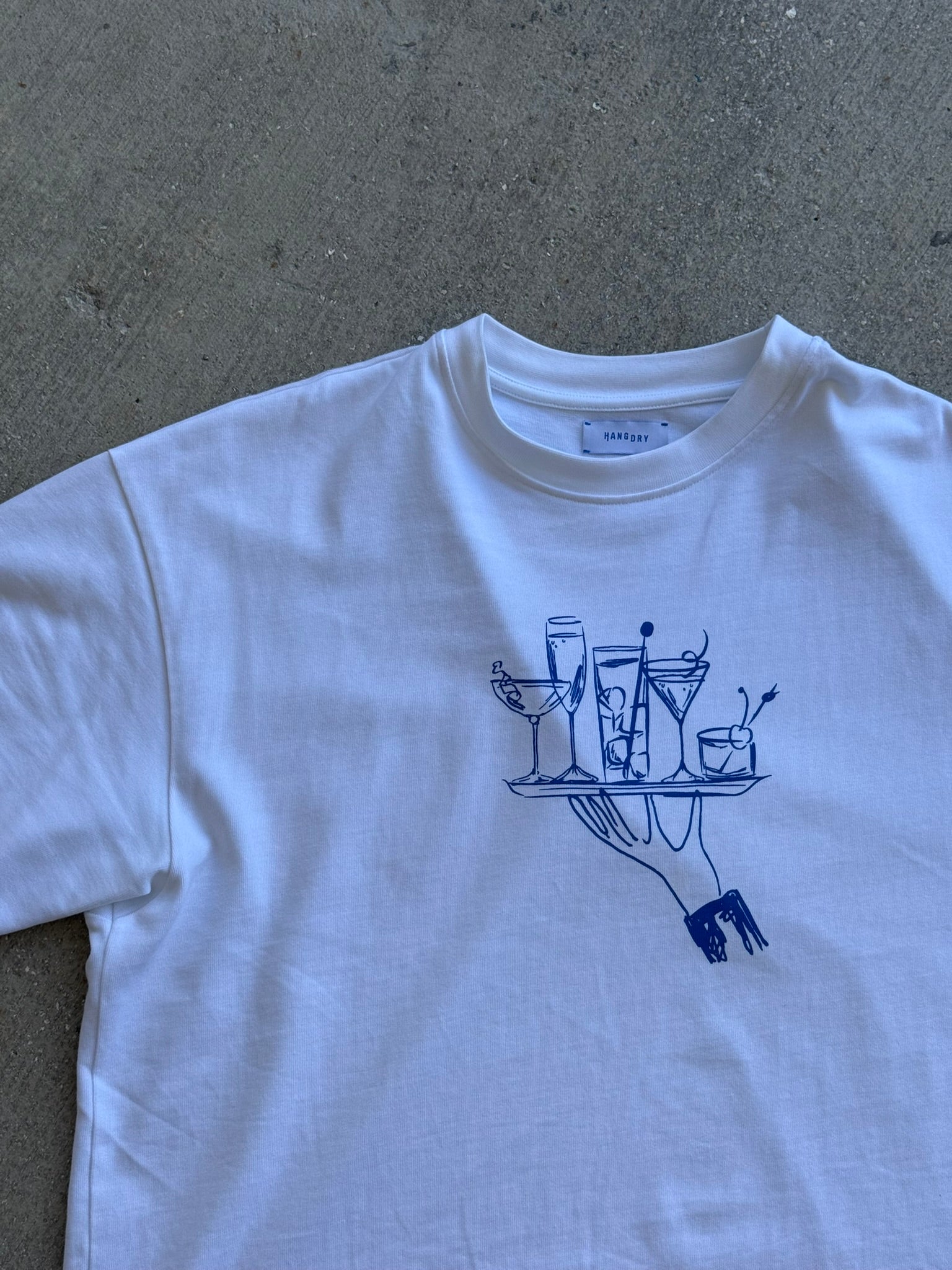 Hang Dry Gallery White Sunday Dinner tee — front view of the hand and cocktail tray graphic on a premium cotton tee