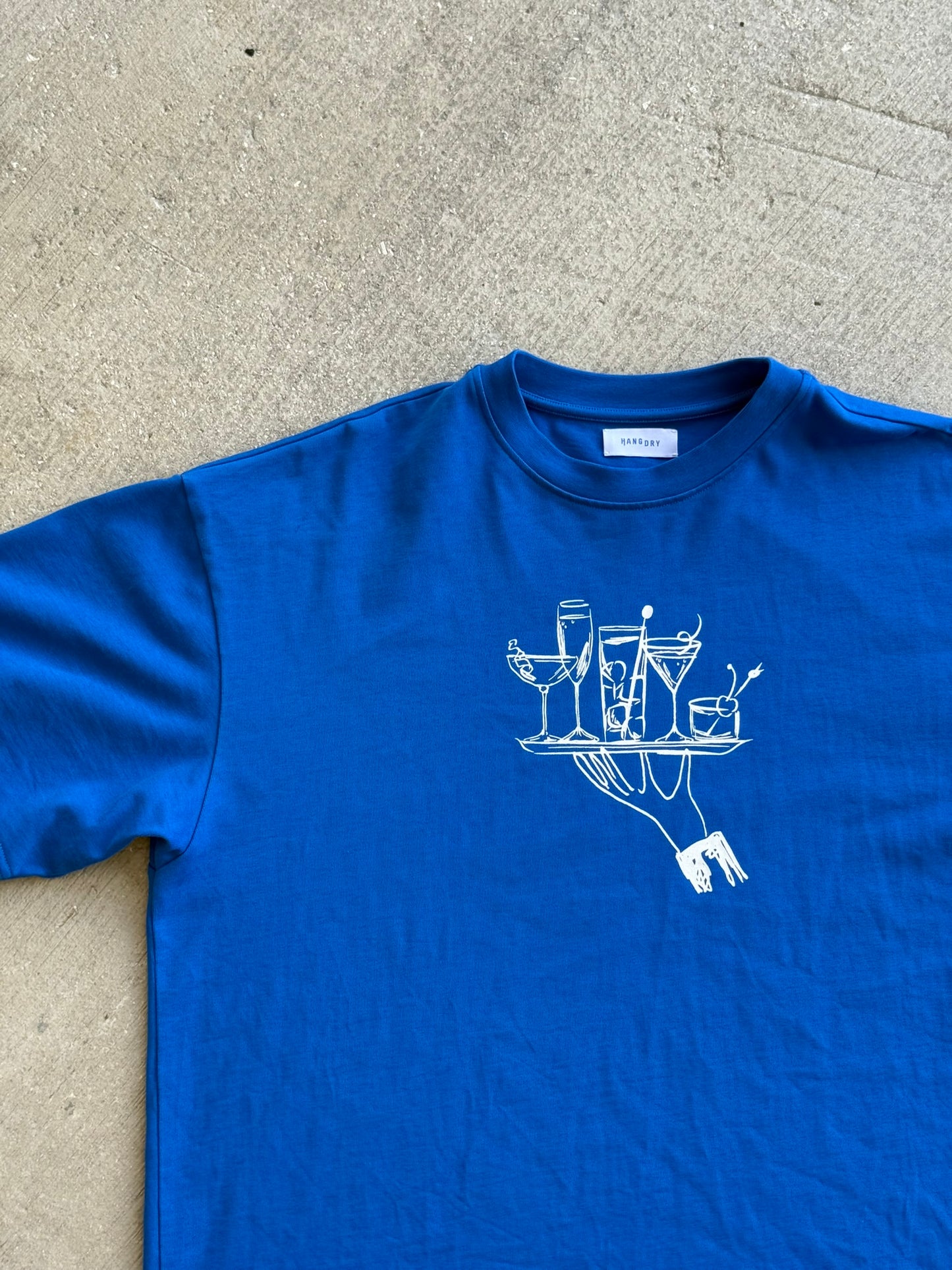 Hang Dry Studio Blue Sunday Dinner tee — front view of the hand and cocktail tray graphic on a premium cotton tee