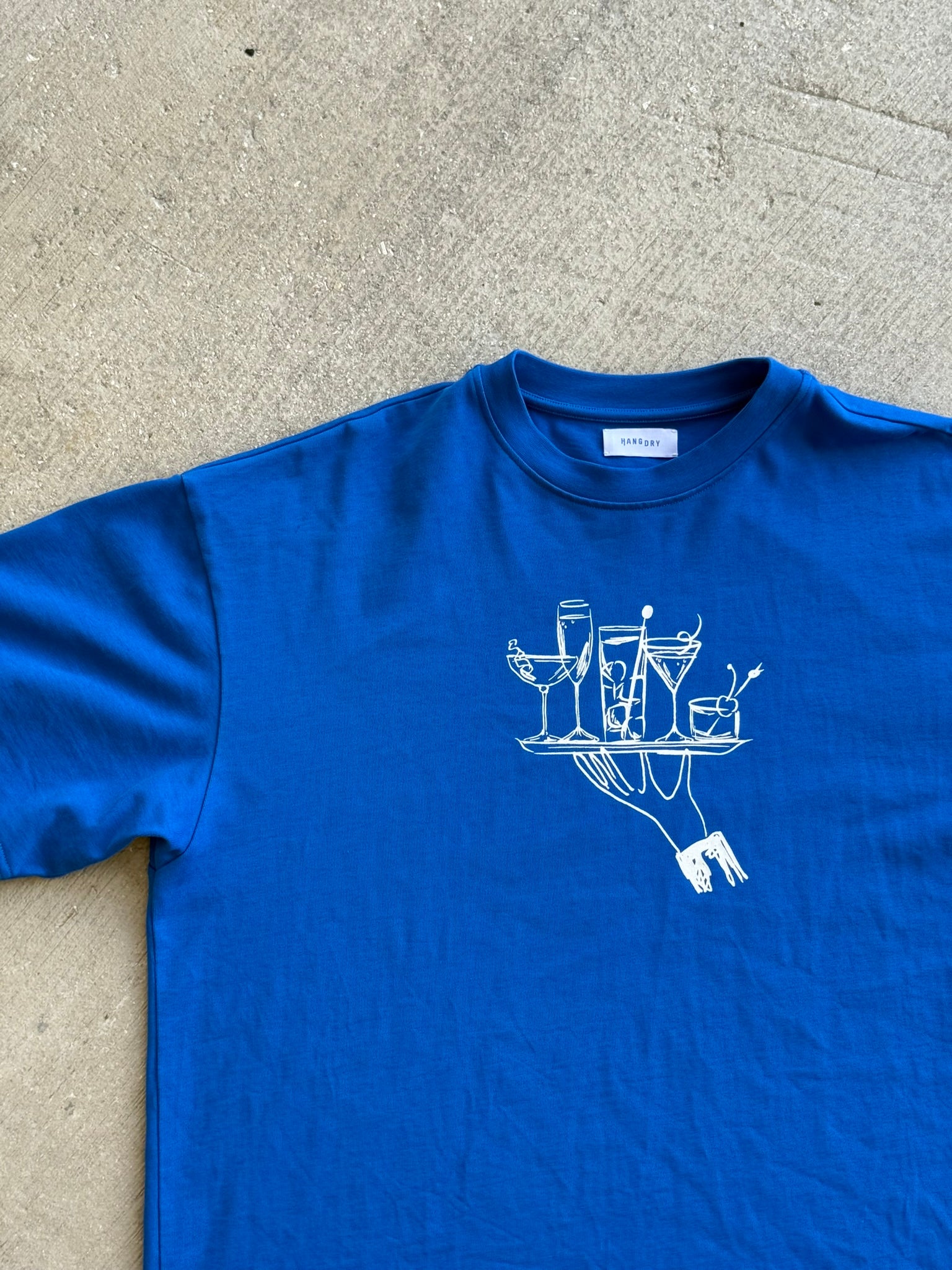 Hang Dry Studio Blue Sunday Dinner tee — front view of the hand and cocktail tray graphic on a premium cotton tee