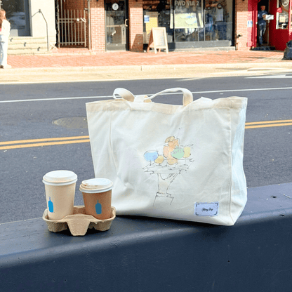Hang Dry Sunday Dinner tote bag resting beside a coffee cup on a city street — lifestyle and style in the everyday