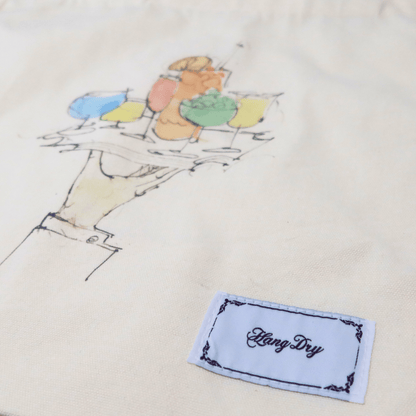 Hang Dry Sunday Dinner tote bag detail — showing brand tag and Sunday Dinner artwork on white canvas